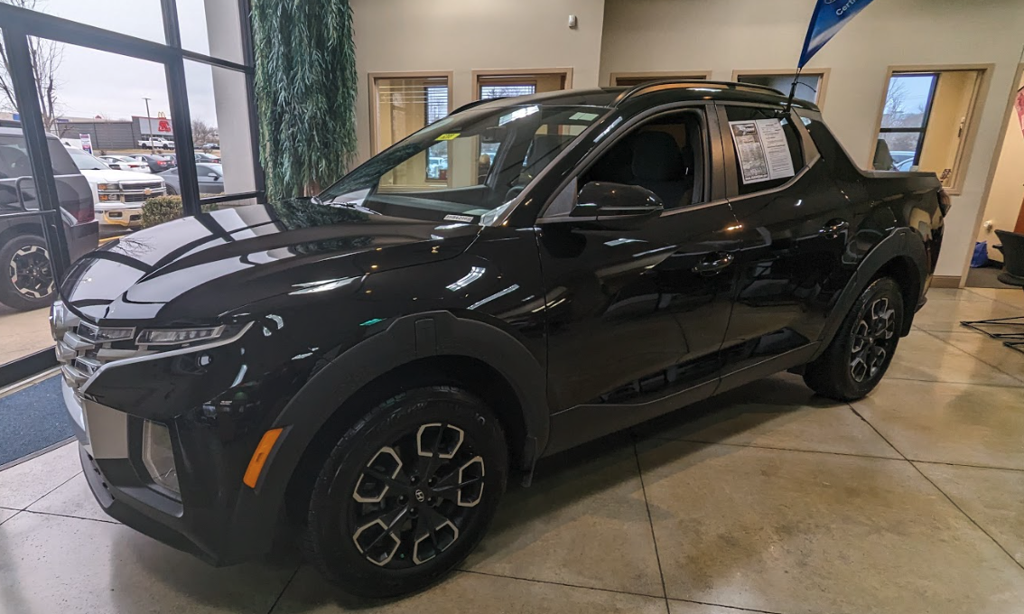 Black Hyundai Santa Cruz parked inside Crain Hyundai of Bentonville showroom with natural light reflecting off its freshly cleaned exterior.